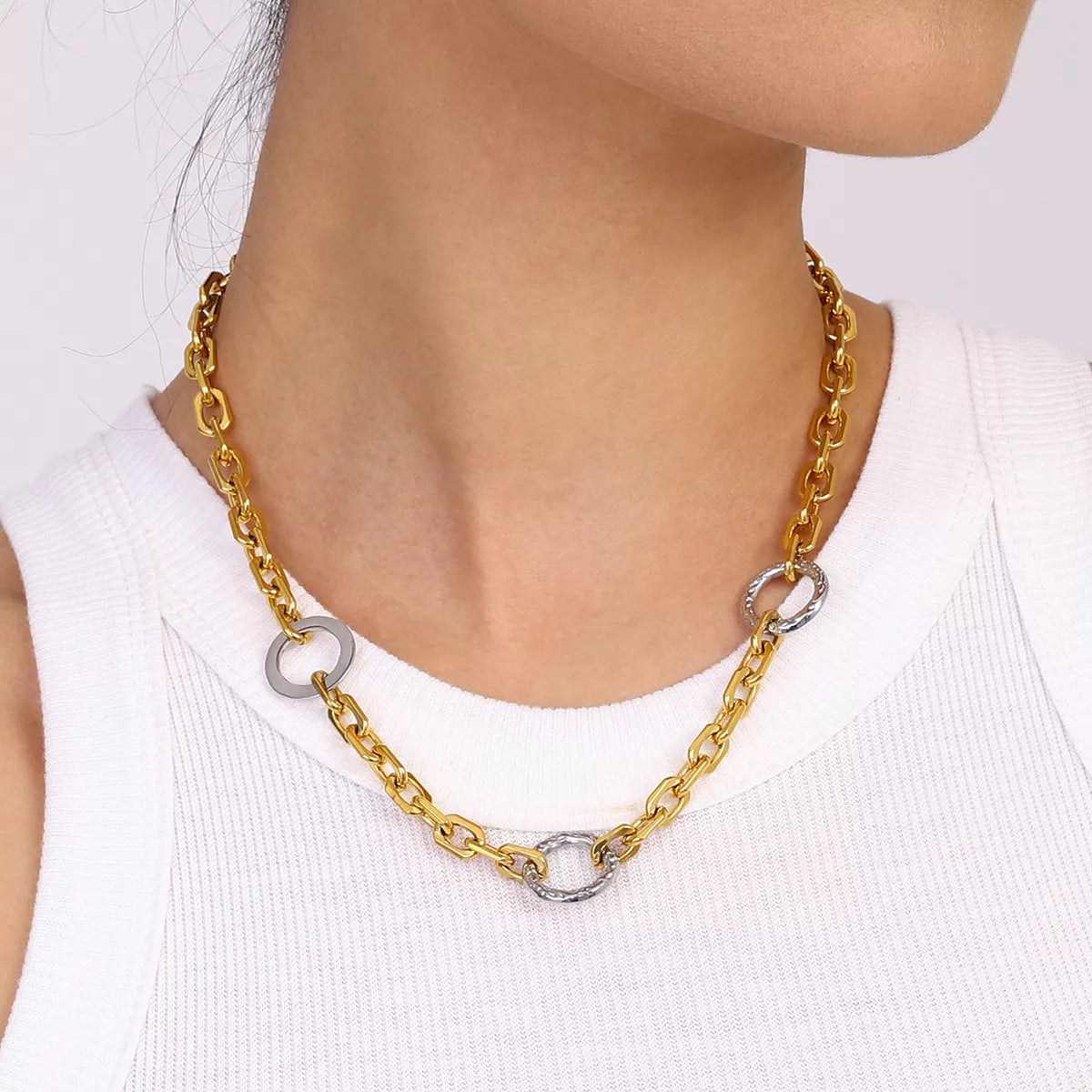 Close-up of a woman wearing an 18K gold-plated stainless steel chain link circle necklace with silver accents.