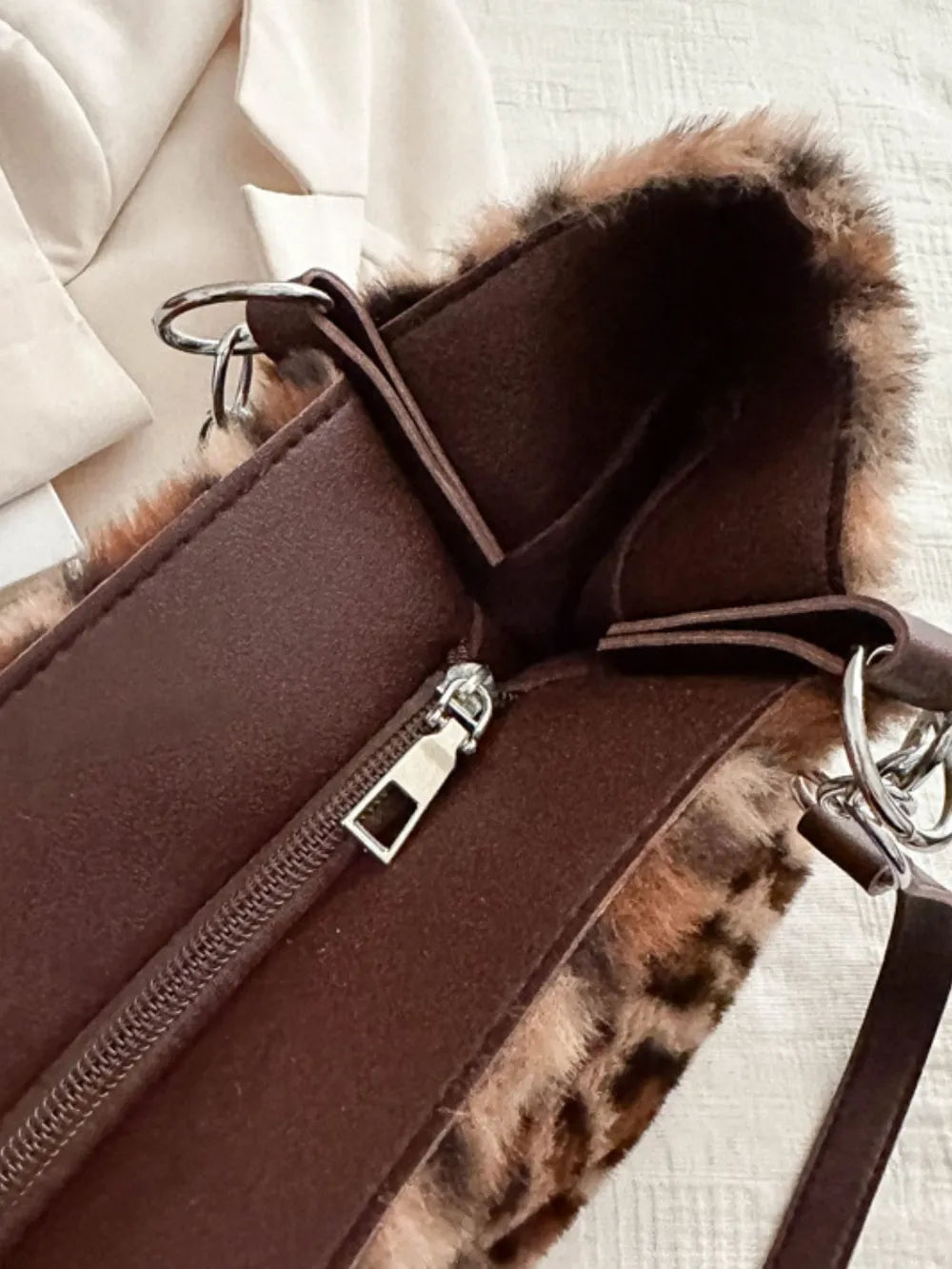 Close-up of a large leopard print faux fur shoulder bag with brown interior and silver zipper detail