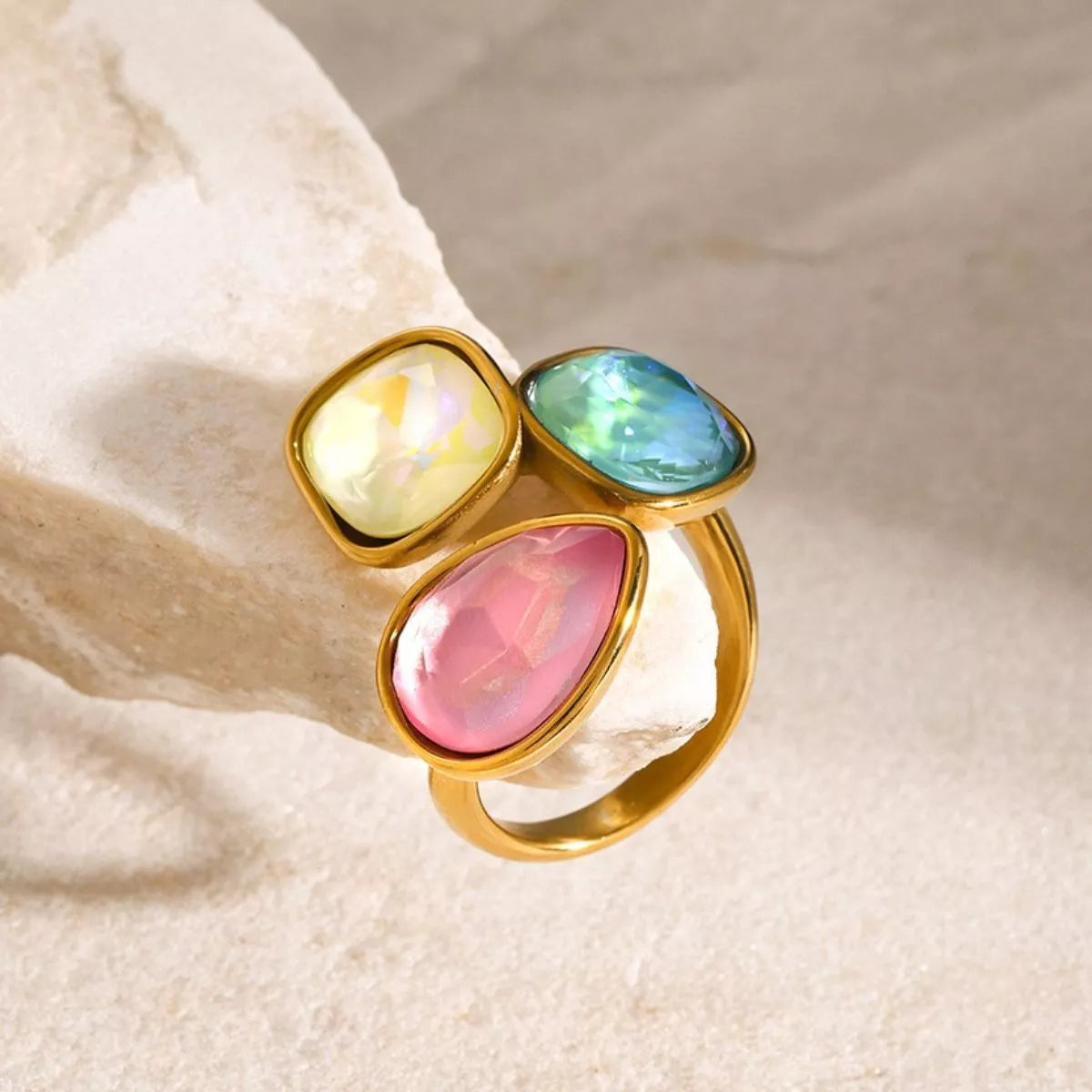 Adjustable 18k gold plated ring with three colorful gemstone rhinestones in a bypass design on a neutral background