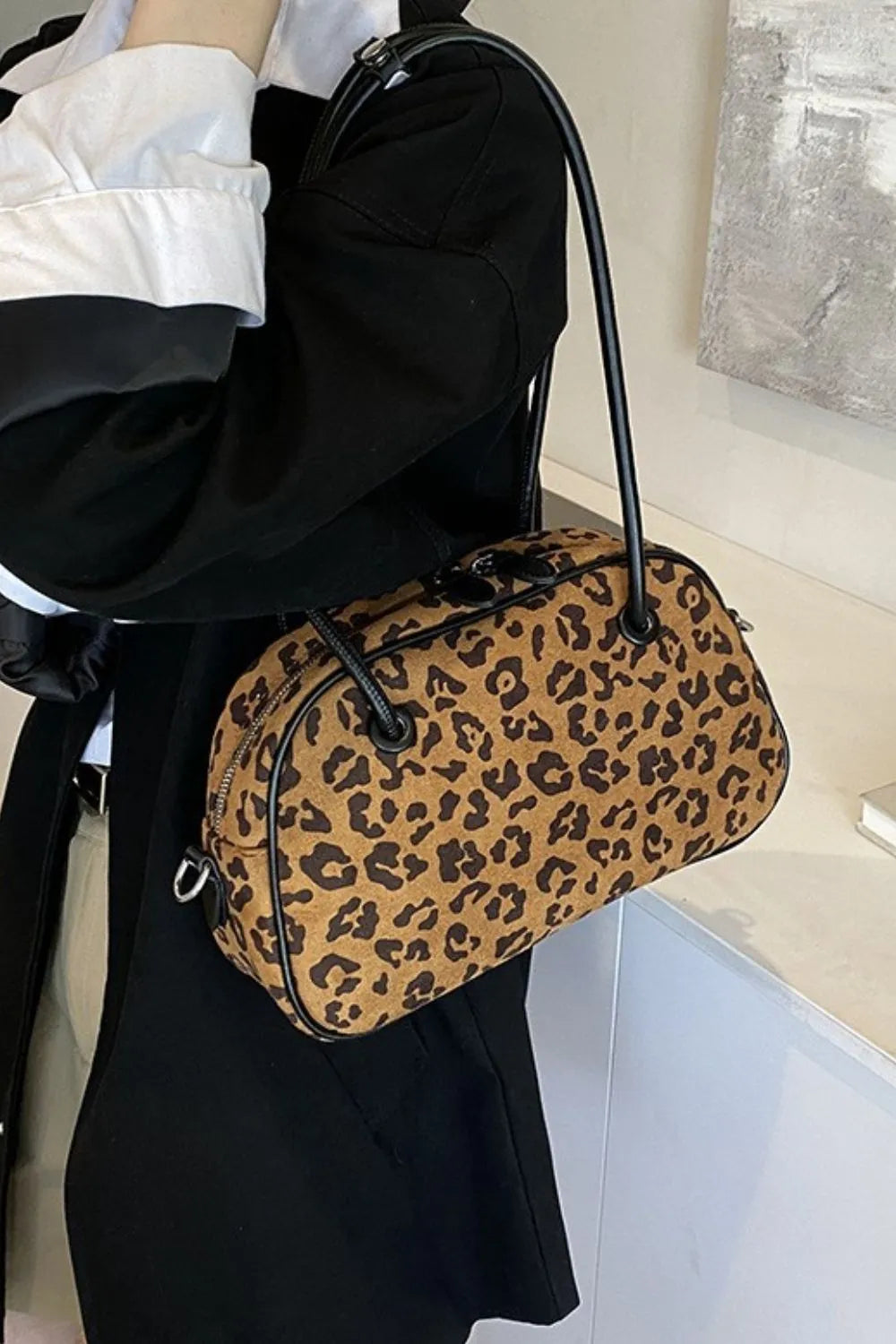 Medium-sized leopard print suede shoulder bag with black handles, stylish and lightweight for everyday use.