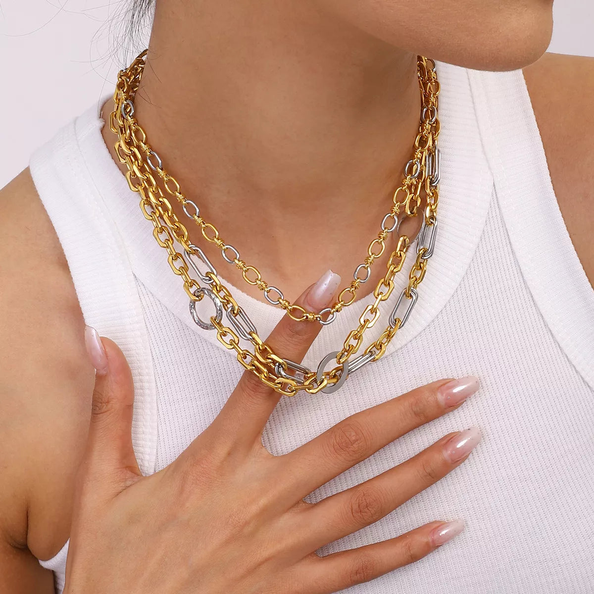Close-up of a woman wearing layered 18K gold-plated and silver stainless steel chain link circle necklaces with a white top
