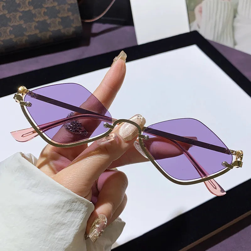 Hand holding stylish cat eye sunglasses with purple lenses and gold metal frames on a white surface background