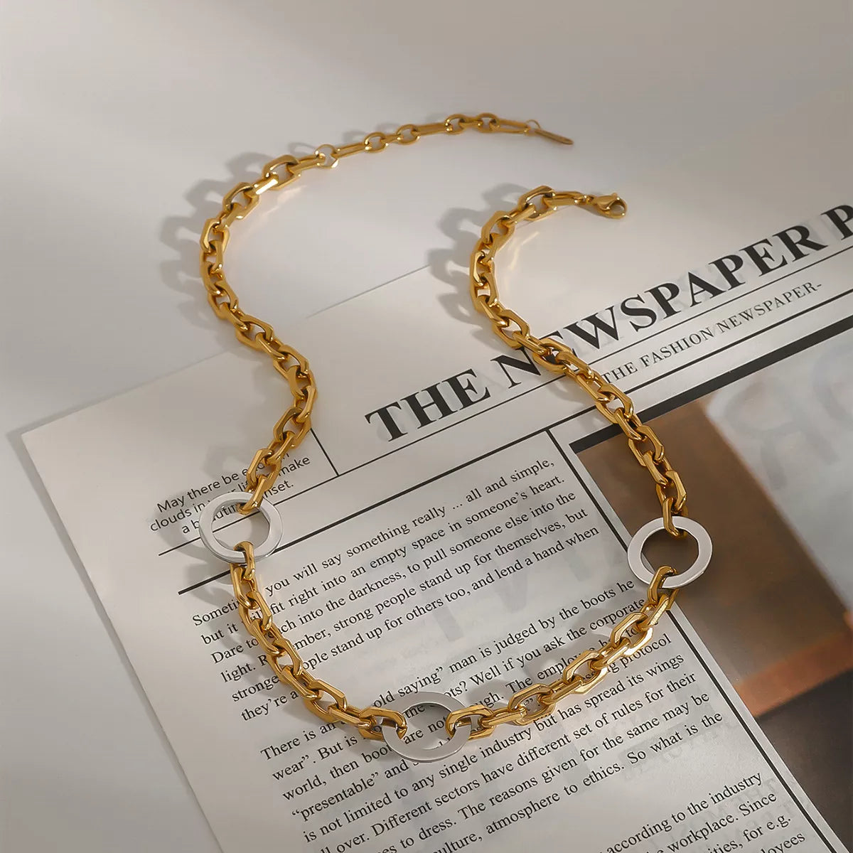 18K gold-plated stainless steel chain link circle necklace displayed on a newspaper background.