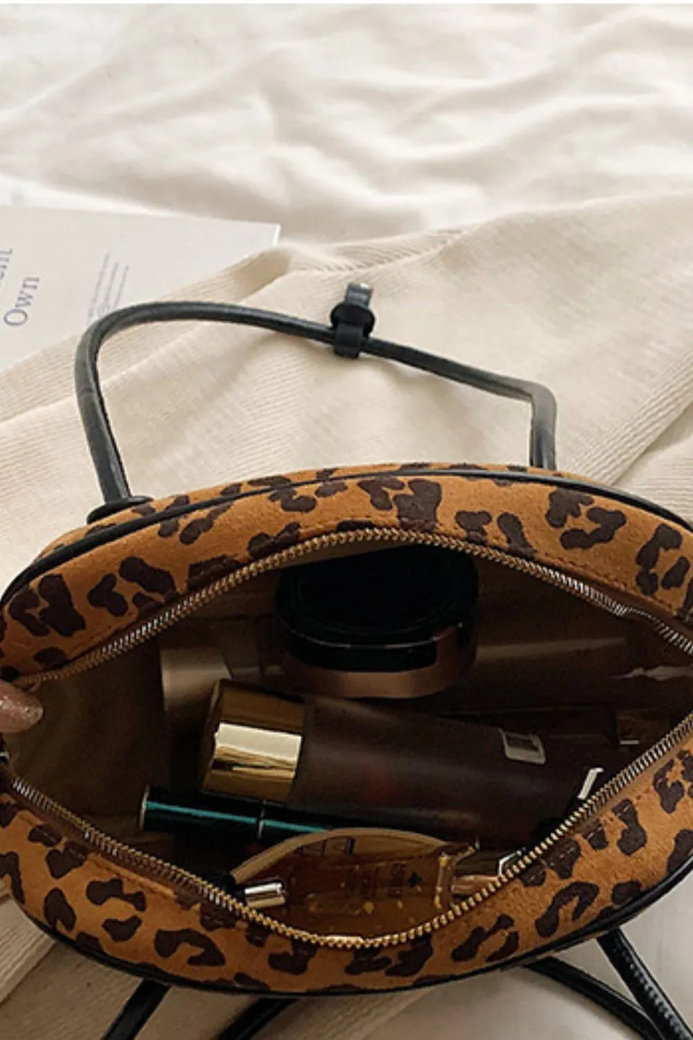 Open leopard print suede shoulder bag showing interior with makeup and beauty essentials inside