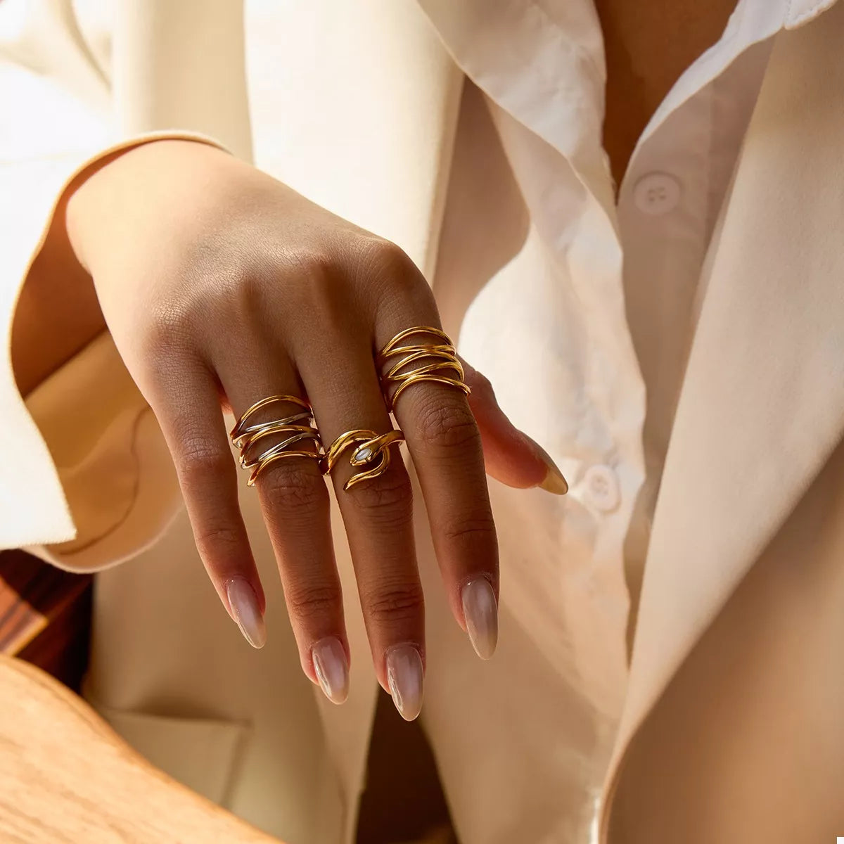 Hand wearing adjustable two-tone open ring in gold-plated stainless steel, styled with multiple matching gold rings