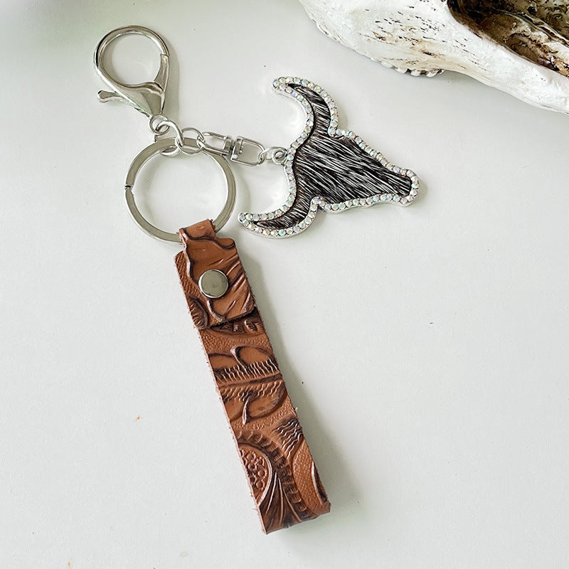 Rhinestone bull keychain with genuine leather and alloy, featuring a brown embossed leather strap and sparkling bull head charm.
