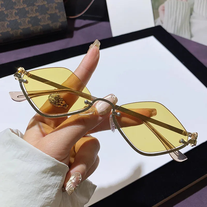 Hand holding metal frame cat eye sunglasses with yellow UV400 polycarbonate lenses on white background
