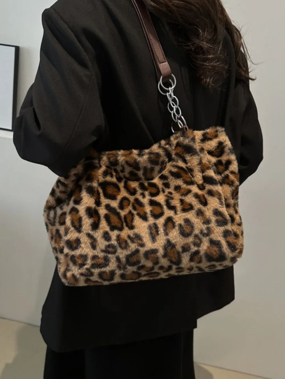 Large leopard print faux fur shoulder bag with brown straps worn over a black blazer outfit
