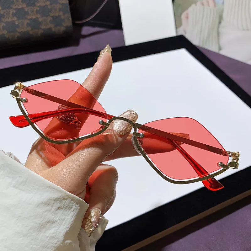 Hand holding stylish cat eye sunglasses with red UV400 polycarbonate lenses and metal-plastic hybrid frame