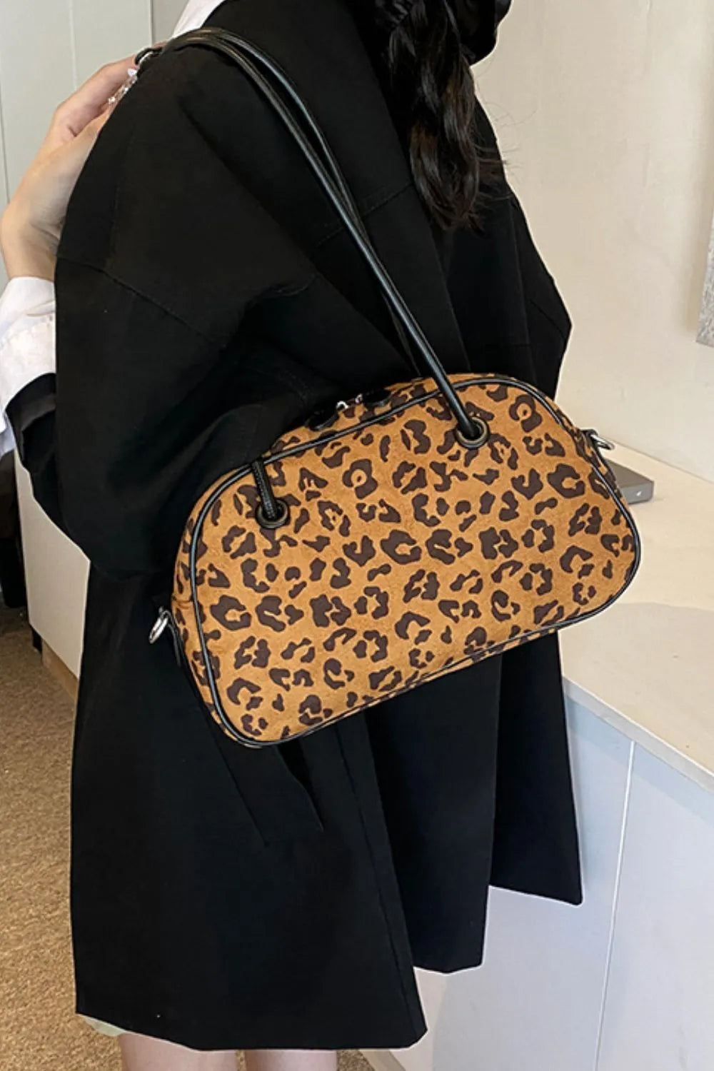 Medium-sized leopard print suede shoulder bag with black handles, perfect for stylish everyday use and lightweight comfort.