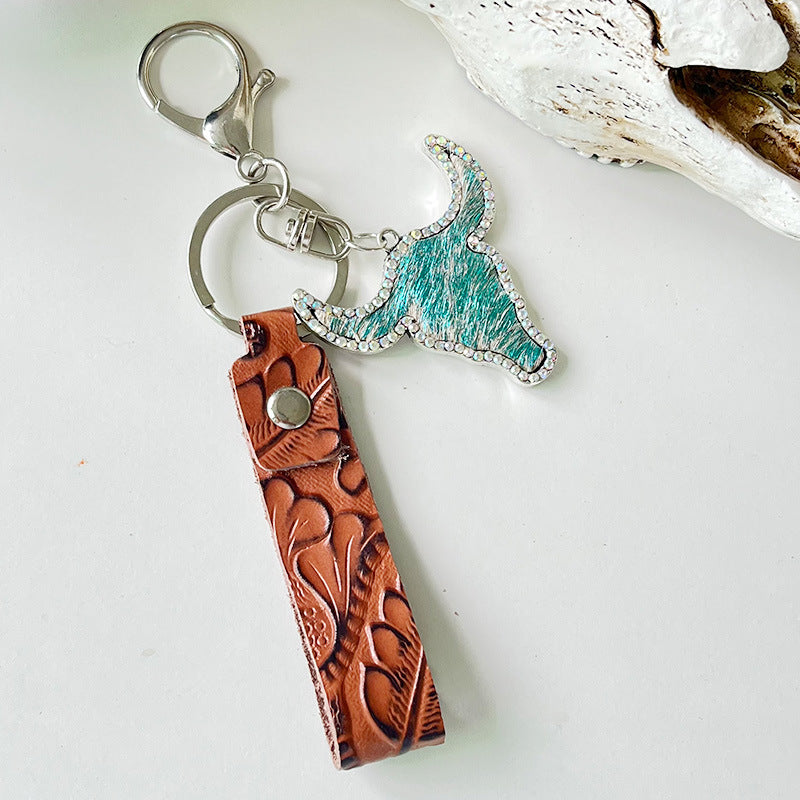 Rhinestone bull keychain with turquoise embellishments and genuine leather strap featuring floral embossing and metal rings.