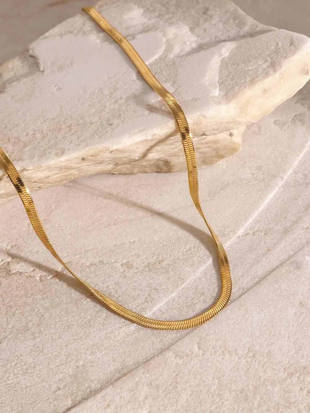 18K gold-plated three-layered cross necklace chain made of durable stainless steel on stone surface background