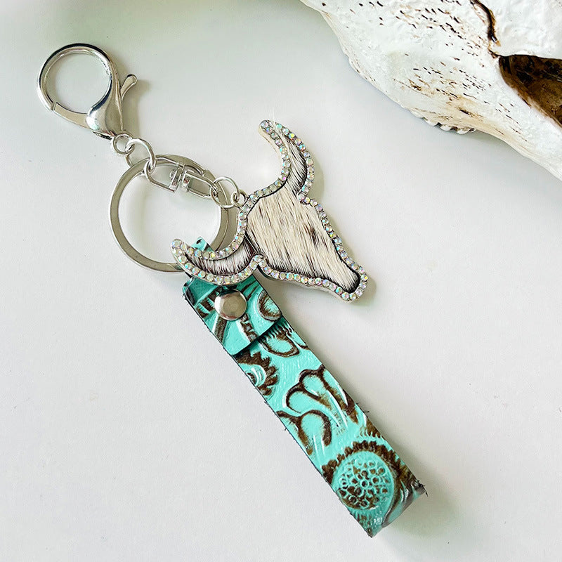 Rhinestone bull head keychain with genuine leather turquoise strap and silver alloy hardware on white background