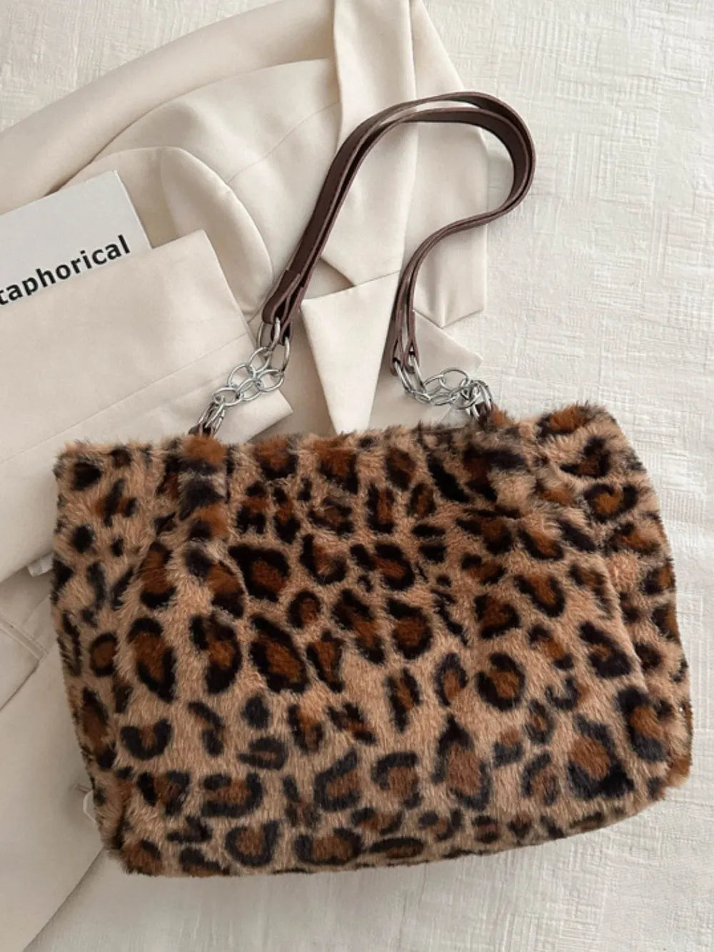 Large leopard print shoulder bag made of soft faux fur with brown leather straps and silver hardware details
