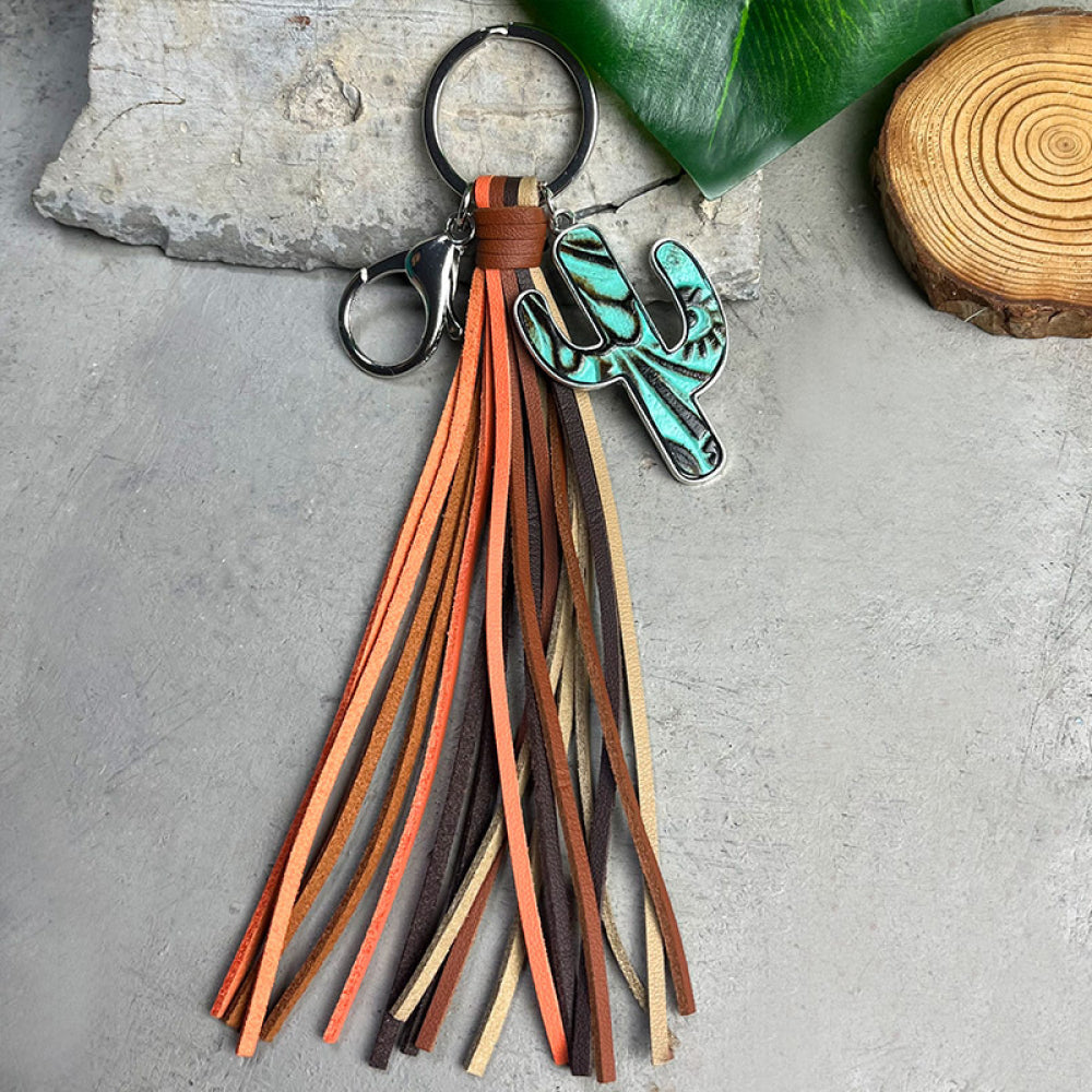 Cactus-shaped alloy keychain with turquoise finish and multi-colored cowhide tassel on a gray background.