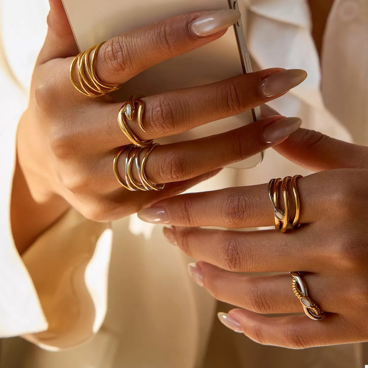 Close-up of hands wearing adjustable two-tone open rings in gold and silver tones on multiple fingers
