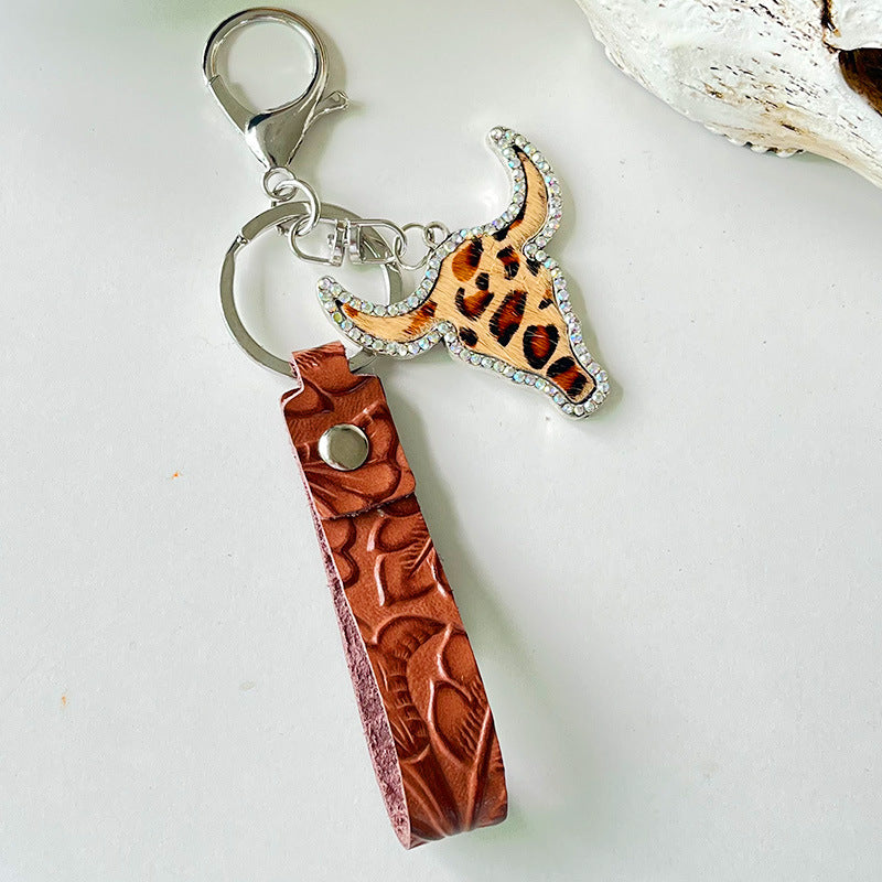 Rhinestone bull head keychain with leopard print and brown embossed genuine leather strap on silver alloy hardware.