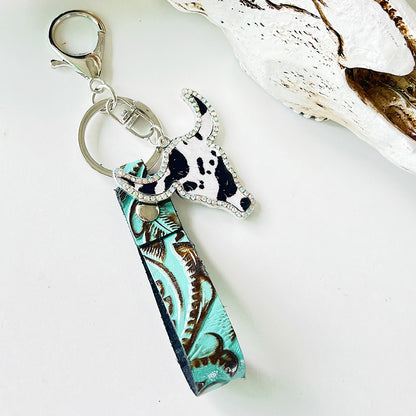 Rhinestone bull head keychain with genuine leather teal patterned strap and silver alloy hardware on white background.