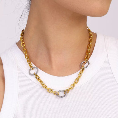 Close-up of a woman wearing an 18K gold-plated stainless steel chain link circle necklace with silver accents.