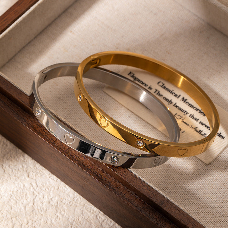 Two gold and silver bangles on a wooden surface with text in the background.