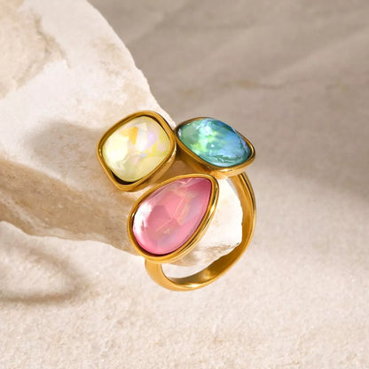 Adjustable 18k gold plated ring with three colorful gemstone rhinestones in a bypass design on a neutral background