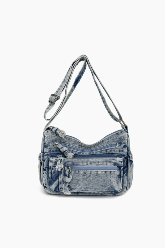 Stylish medium-sized denim crossbody bag with adjustable strap and multiple front zippered pockets for daily use.