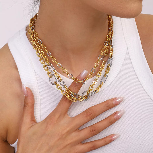 Close-up of a woman wearing layered 18K gold-plated and silver stainless steel chain link circle necklaces with a white top