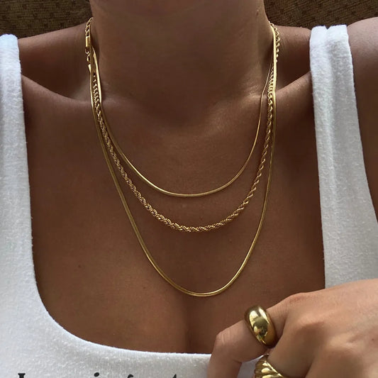 Three-layered twisted rope necklace in radiant 18K gold titanium steel worn over a white tank top.