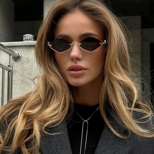 Woman wearing metal frame cat eye sunglasses with dark lenses and long wavy hair outdoors on urban background