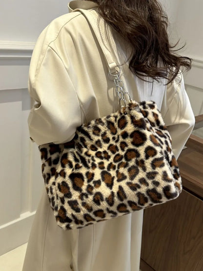 Large leopard print faux fur shoulder bag with cream strap worn over shoulder on beige coat background