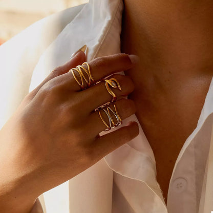 Close-up of a hand wearing an adjustable two-tone open ring made of 18K gold-plated stainless steel on a white shirt background