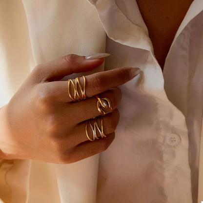 Hand wearing adjustable two-tone open rings in gold and silver plated stainless steel on fingers against white shirt background