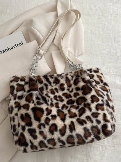 Large leopard print shoulder bag in soft faux fur with beige straps and silver chain accents on a light fabric background